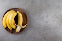 platanos-maduros-placa-madera-sobre-superficie-marmol